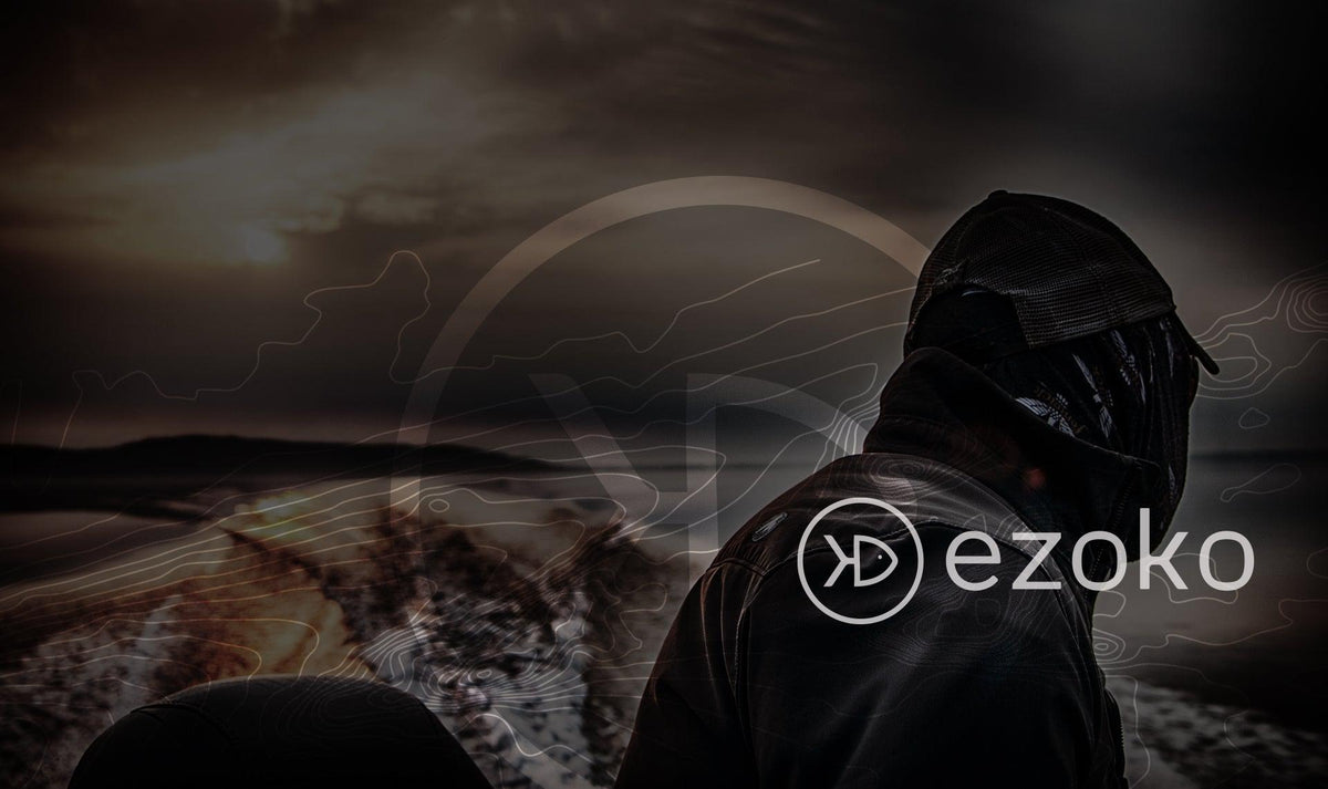 Back of an an esox angler driving a fishing boat, wearing watreproof jacket, buff and cap and looking at the water