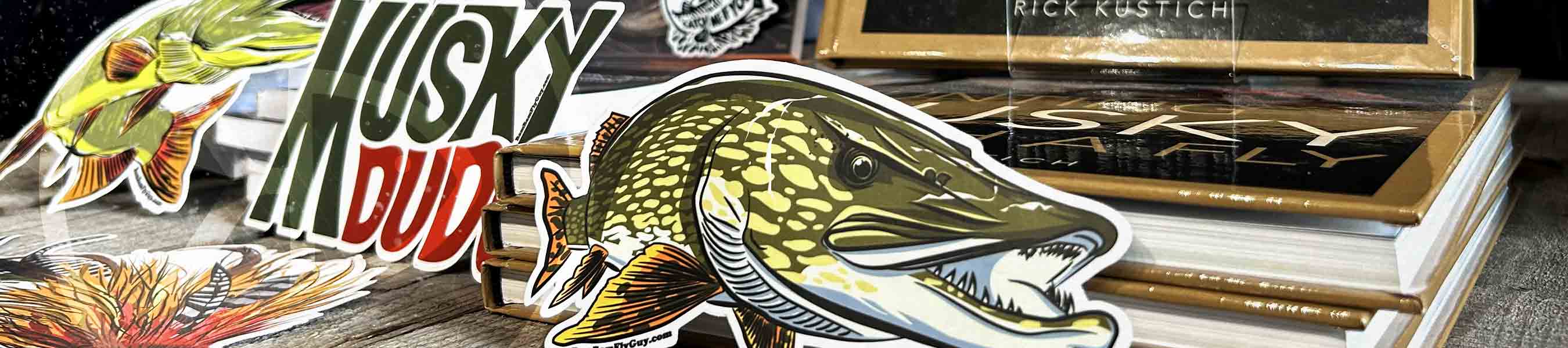 Bam Bam Fly guy pike and musky stickers dropped on a pile of books "Hunting Musky with a Fly" from Rick Kustich