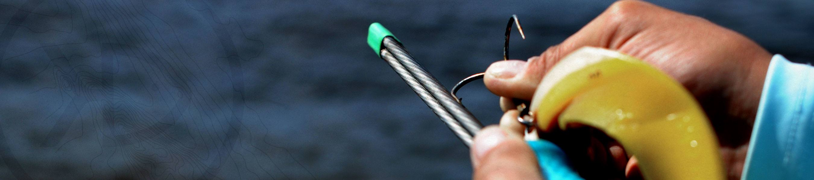 Musky angler holding a Stick File Hook sharpener and sharpening a big musky-sized treble hook