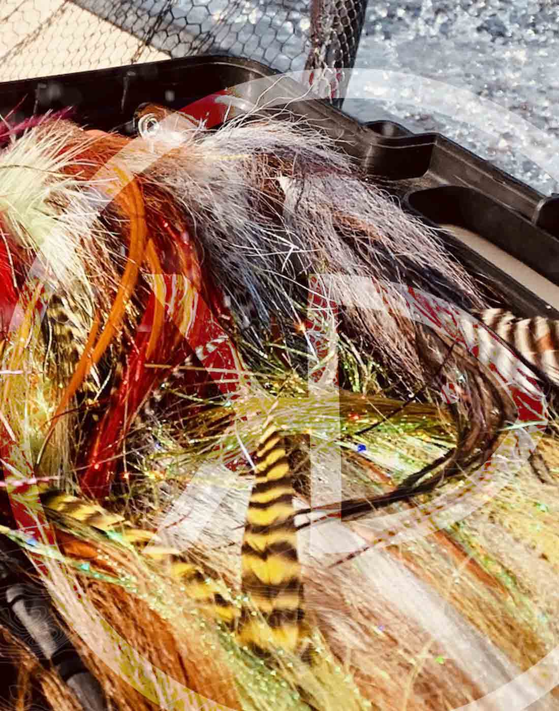 Several colorful big pike and musky flies on a boat fly box.
